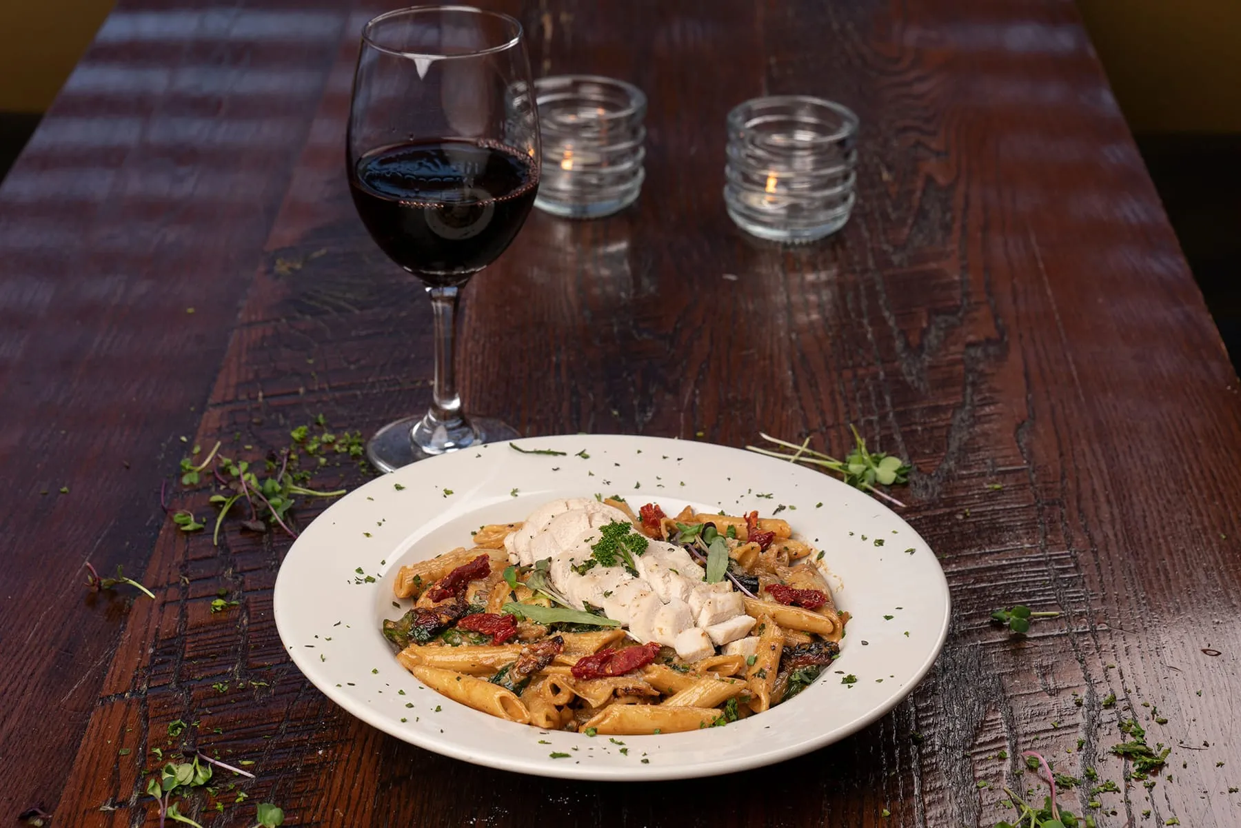 Chicken sun-dried tomato pasta with a glass of red wine